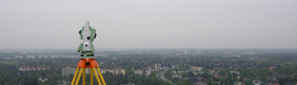 Totalstation auf Stativ über nebligem Stadtpanorama